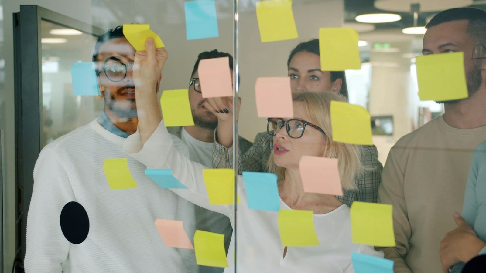 A team sticking yellow and blue notes on a glass wall