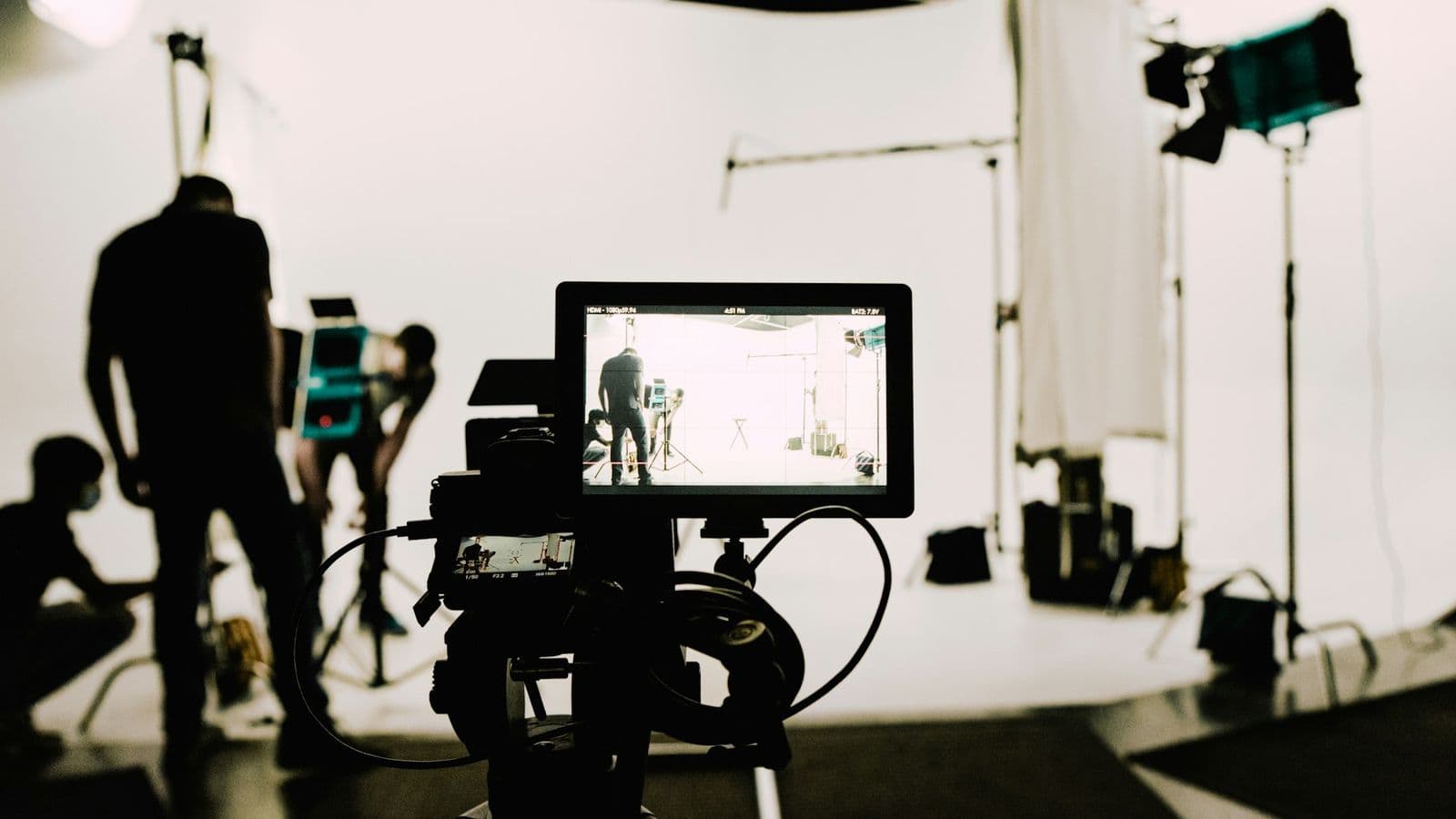A film set with a camera, lights and a crew in a white studio